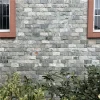 Grey chiseled split stone veneer with uniform raised texture, durable outdoor facade cladding for residential buildings