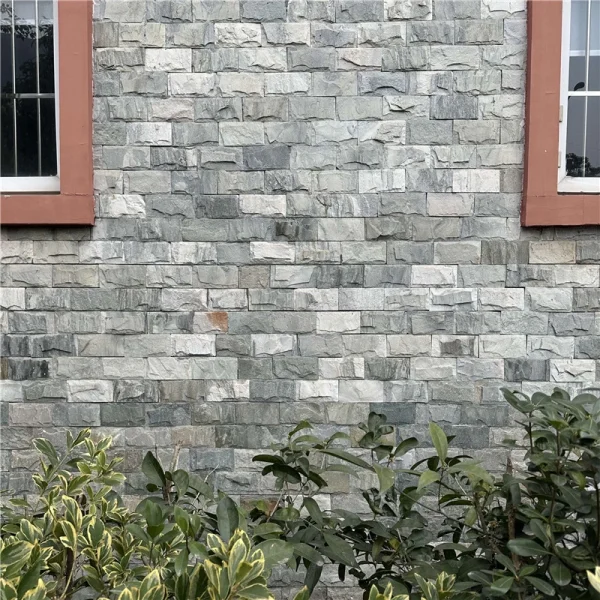 Grey chiseled split stone veneer with uniform raised texture, durable outdoor facade cladding for residential buildings