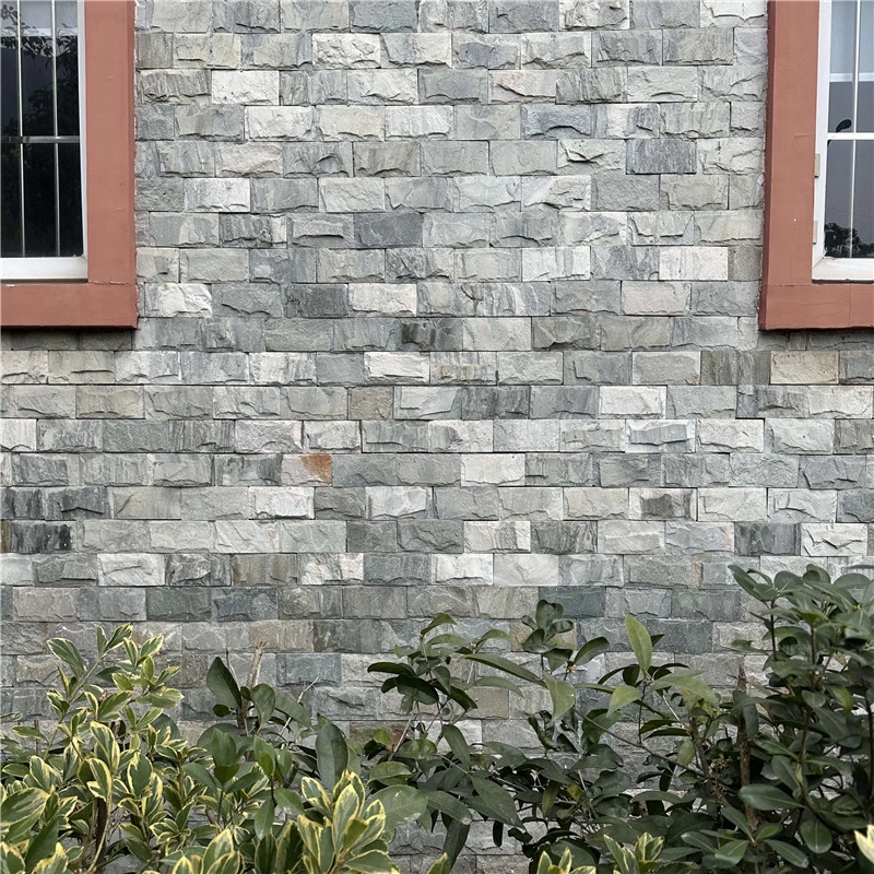Grey chiseled split stone veneer with uniform raised texture, durable outdoor facade cladding for residential buildings