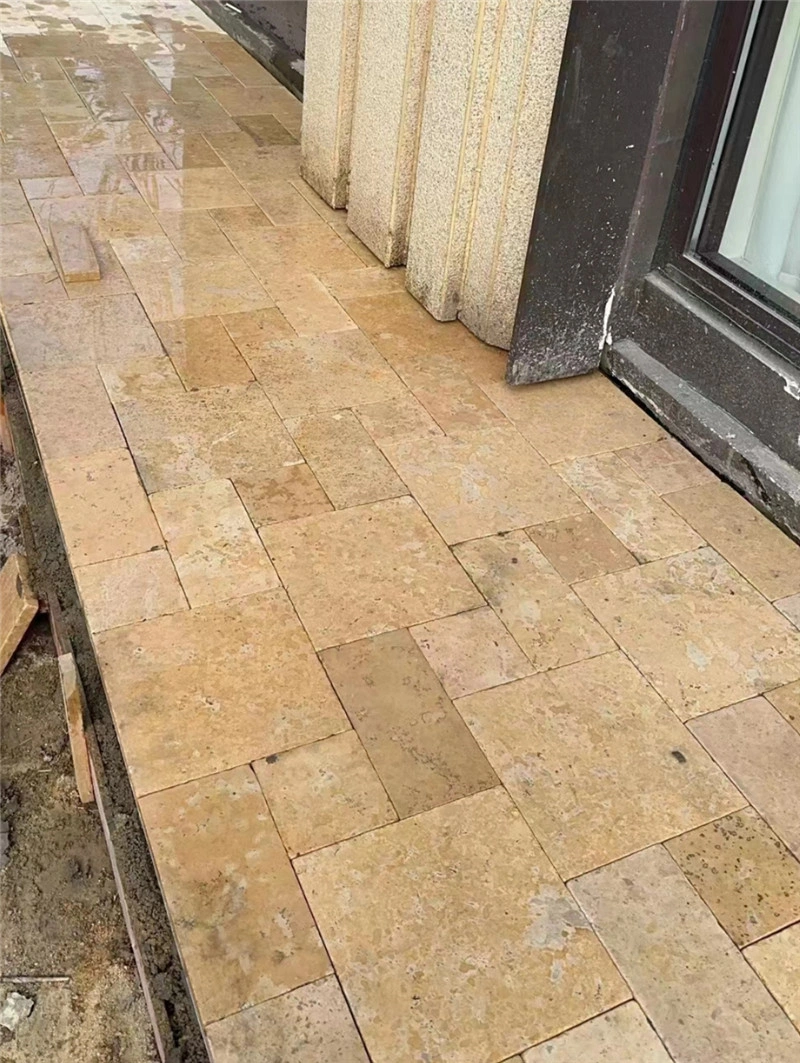 Tumbled beige limestone paving beside entrance doorway