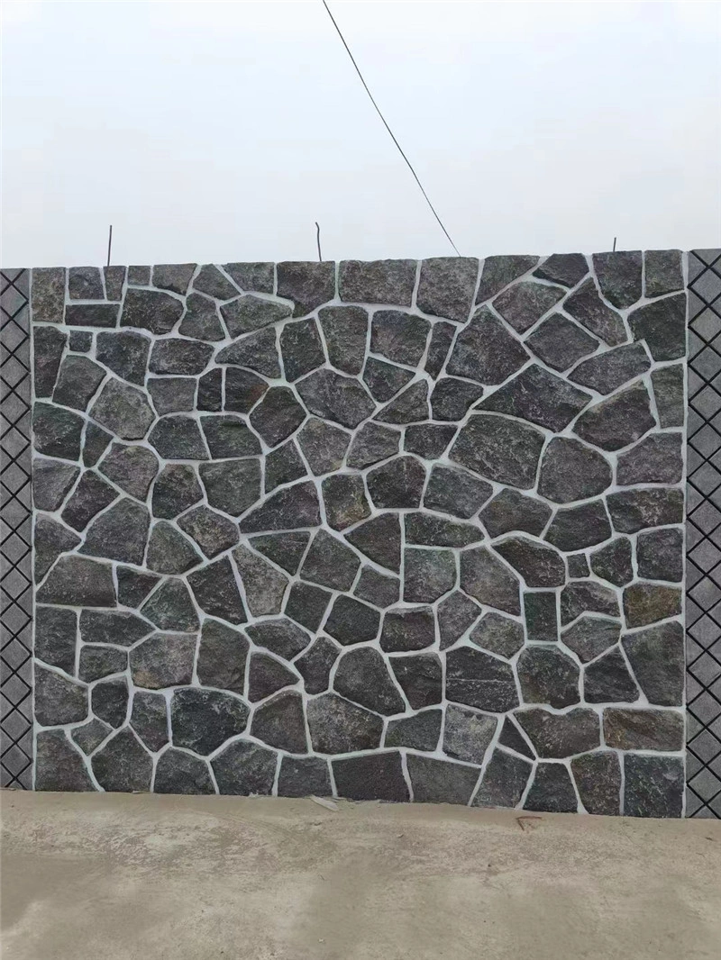 Large exterior boundary wall with charcoal grey crazy paving stone cladding