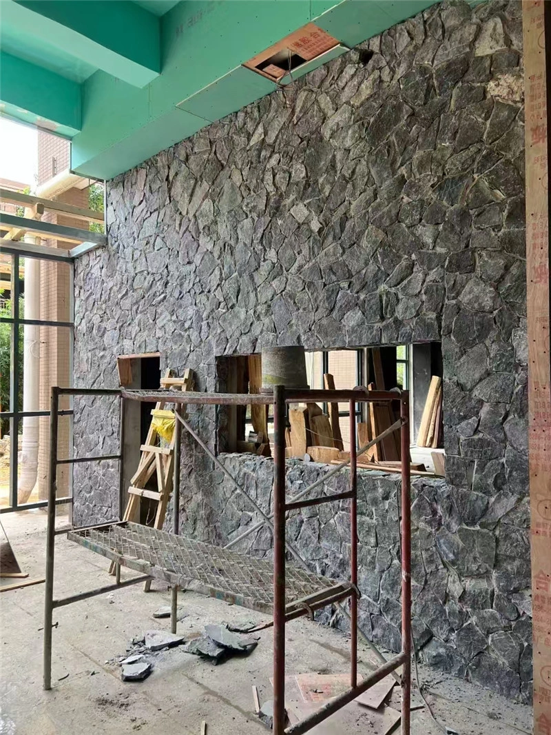 Installing charcoal grey crazy paving stone on building exterior wall site