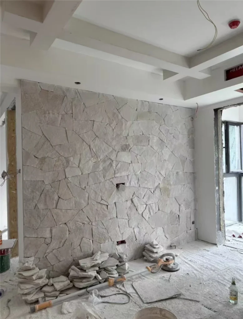 Natural white sandstone cladding under installation for interior accent wall
