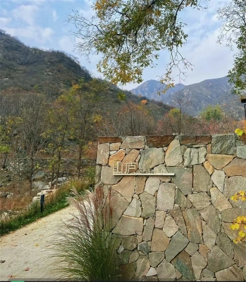 Outdoor garden boundary wall built with natural crazy paving stone in mountain landscape