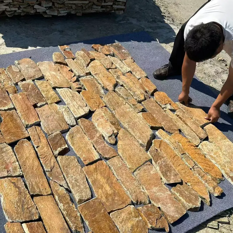 Workman laying rust colored natural stone ledger panels on backing mesh