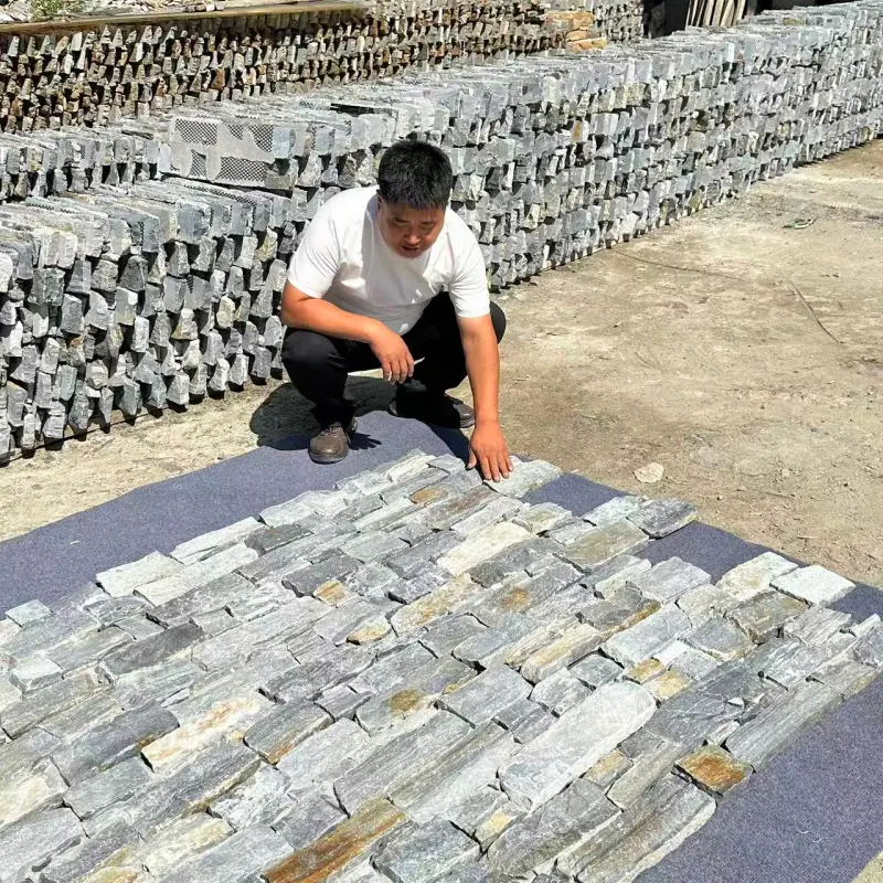 Light blue stacked stone exterior wall cladding, worker arranging ledger stone on mesh backing