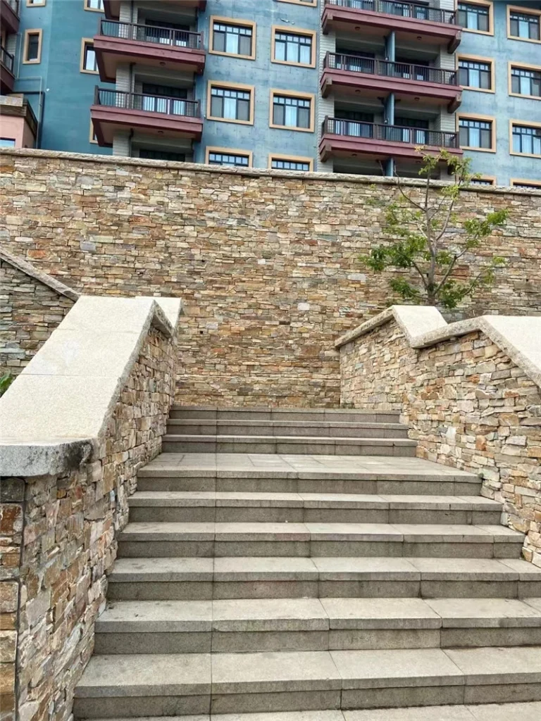 Rust colored natural stone ledger panels for outdoor retaining wall and stair landscape project