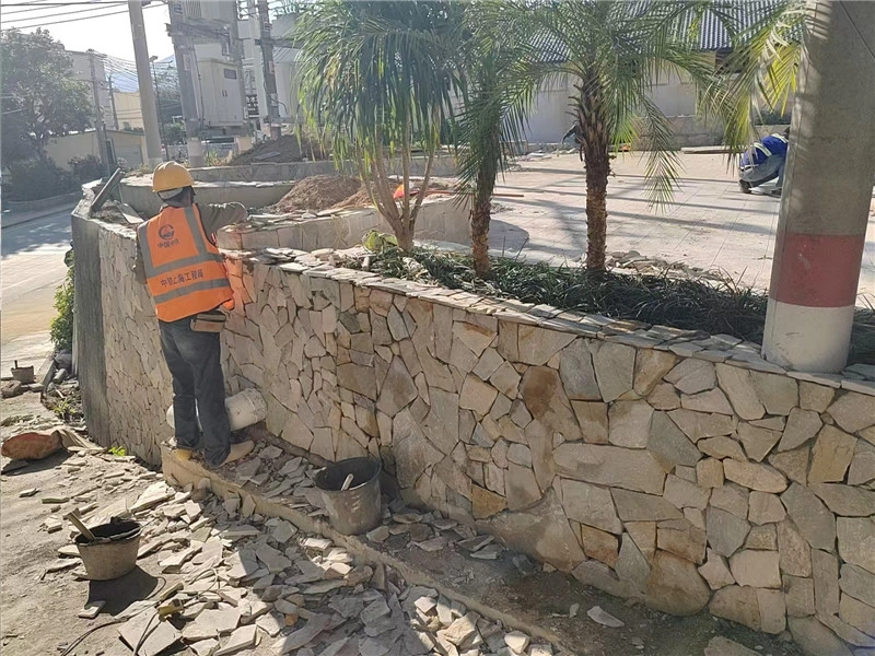 Worker installing Yellow Wood Grain Wall Stone for landscape boundary wall